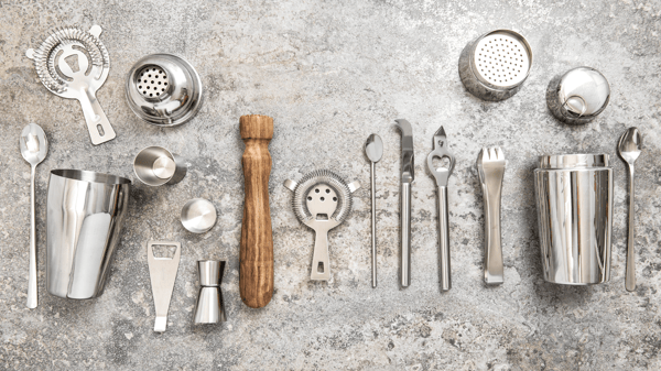 Stainless steel bar tools lined up on a stone back drop