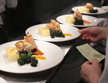 Hand placing food order ticket near identical plates food