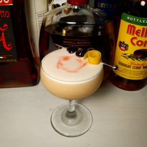 Egg white cocktail whiskey sour seved up in coupe with lemon twist garnish
