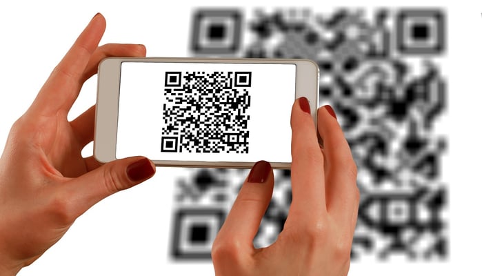 Image of a woman's hands holding an iPhone and scanning a qr code 