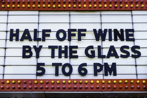 Happy hour in a tourist town Daily bargain on wine announced on a vintage movie marquee on a main street in America