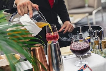 Well dressed server pouring sangria into a wine glass at a table