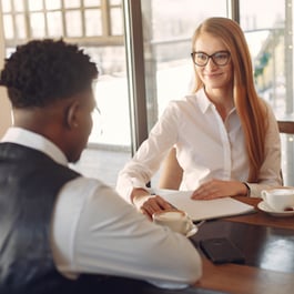 Woman with glasses interviewing a gentleman for a job