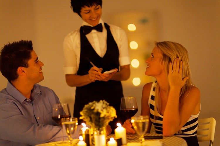 Image of Female Waitstaff at Restaurant Taking an Order of Couple Dining at Restaurant at Candlelit Table