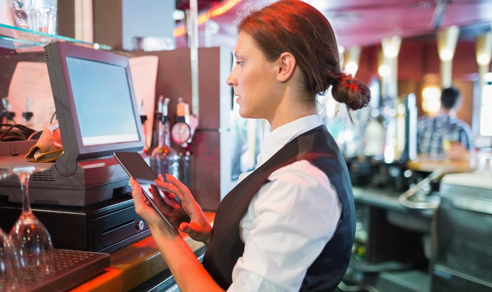 Focused barmaid using touchscreen till in a bar